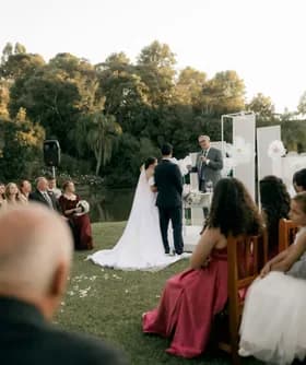 Ceremonia de boda al aire libre junto a un lago, con los invitados sentados