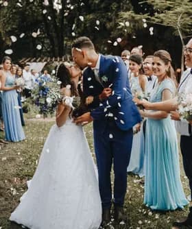 Los recién casados se besan mientras los invitados lanzan pétalos