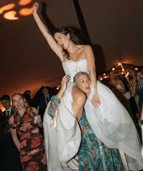 La novia a hombros de una amiga en la pista de baile