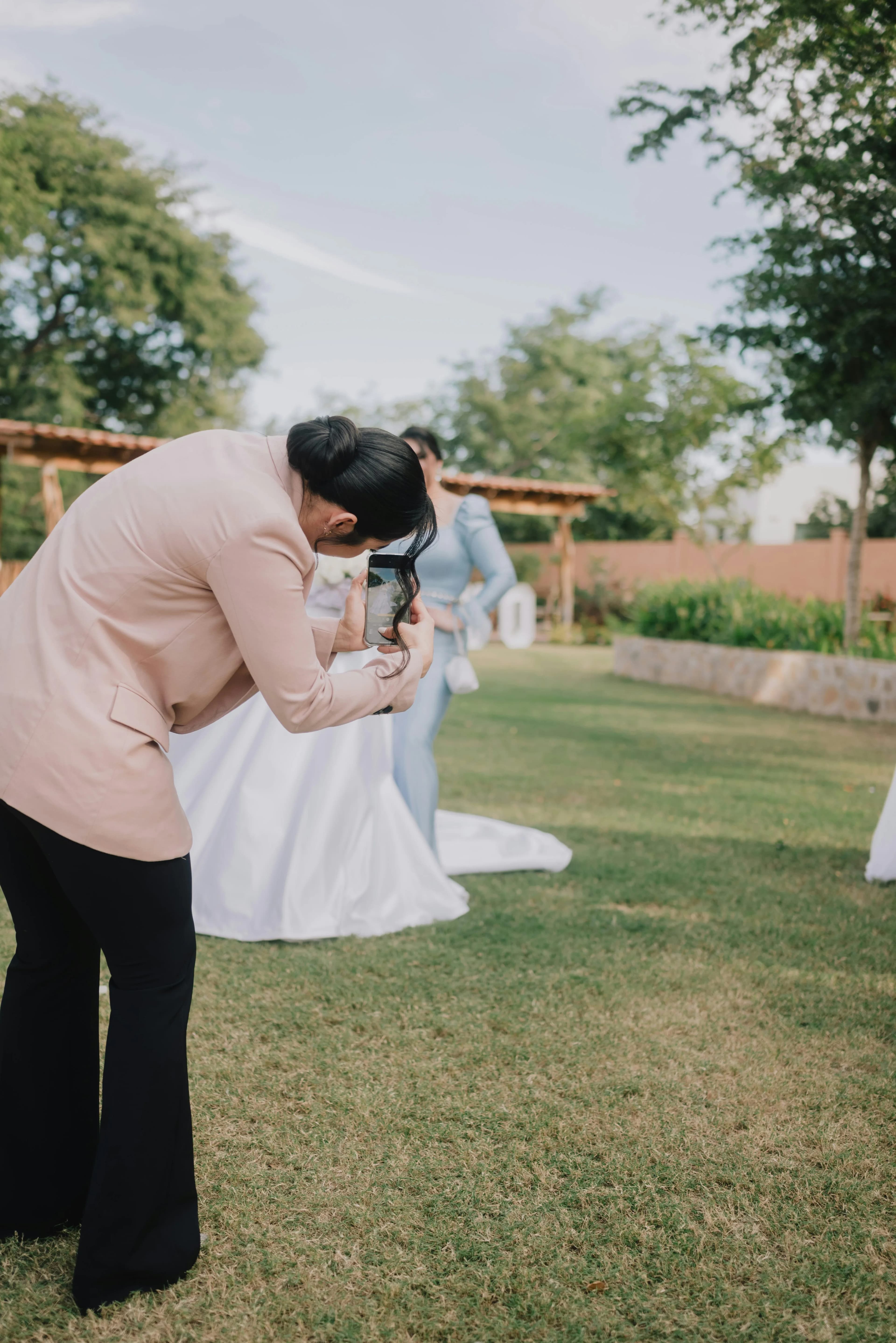 Una invitada se agacha para fotografiar a la novia con su móvil